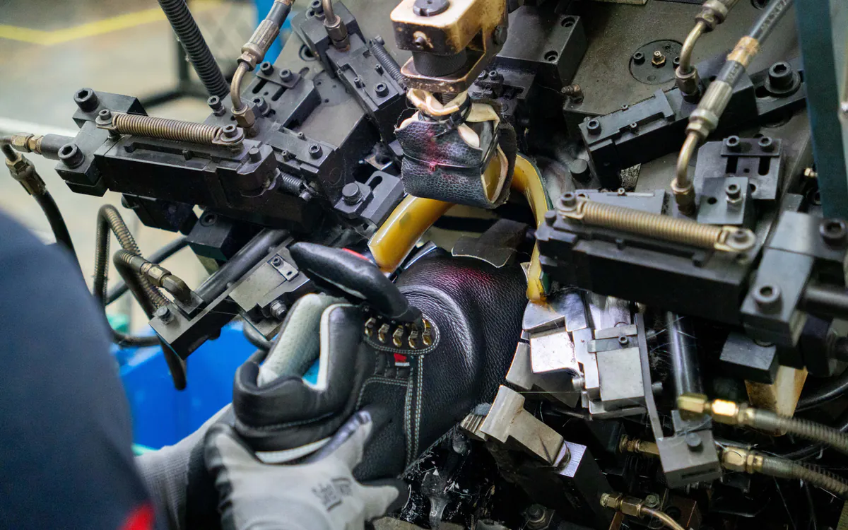 Close view of precision lasting machinery shaping a RHINO SHOE safety boot