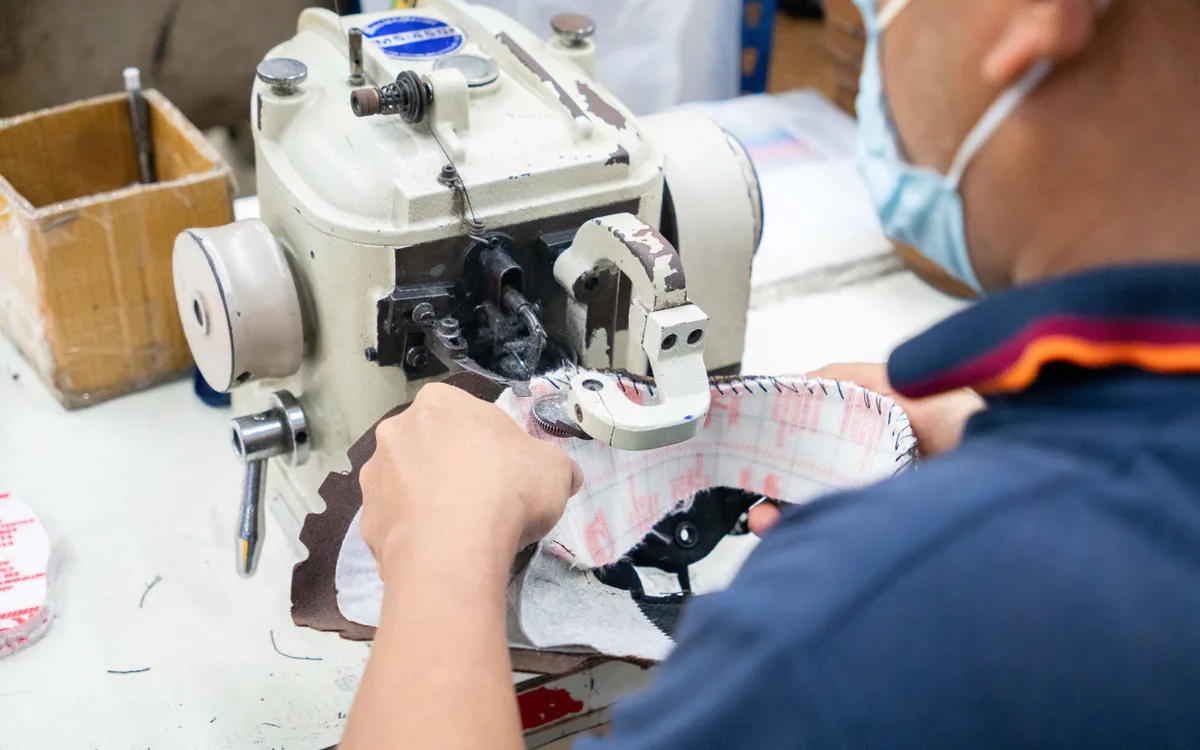 RHINO SHOE operator performing Strobel stitching on a safety shoe upper